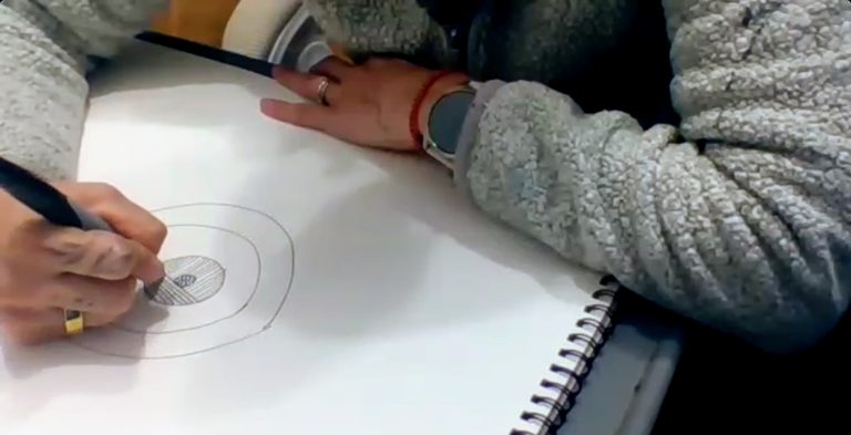 Manos dibujando círculos concéntricos en un cuaderno