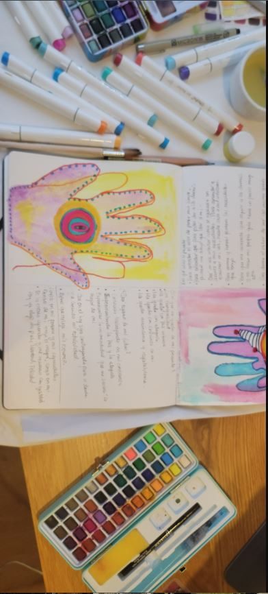 Diario de arte con una mano pintada, acuarelas y marcadores